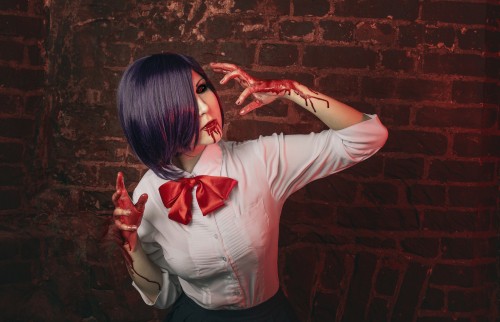 Image woman in white long sleeve shirt standing beside red brick wall