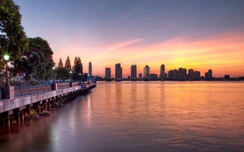 Image city skyline across body of water during night time