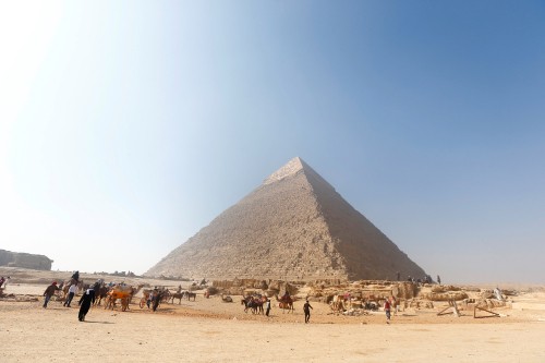 Image people on brown sand near pyramid under blue sky during daytime