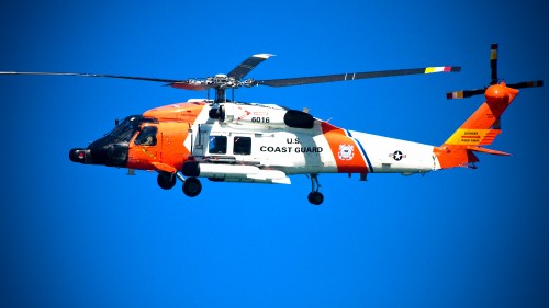 Image orange and white helicopter flying in the sky during daytime