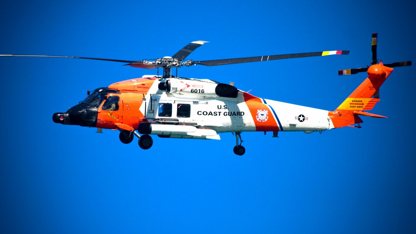 orange and white helicopter flying in the sky during daytime