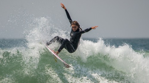 Image woman in black wetsuit surfing on water waves during daytime