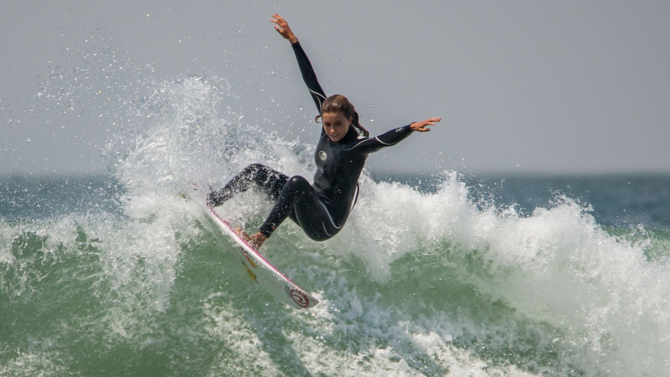 woman in black wetsuit surfing on water waves during daytime