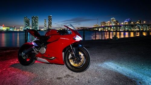 Image red and black sports bike parked on gray concrete pavement during night time