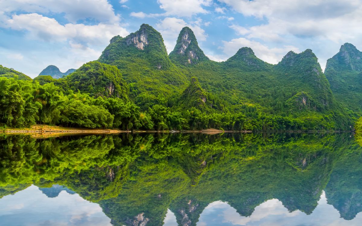 green mountain beside body of water during daytime