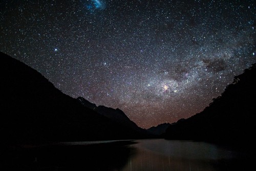 Image body of water near mountain under starry night