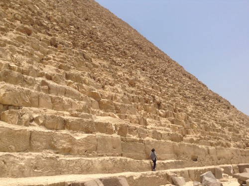 Image man in black jacket standing on brown rock formation during daytime