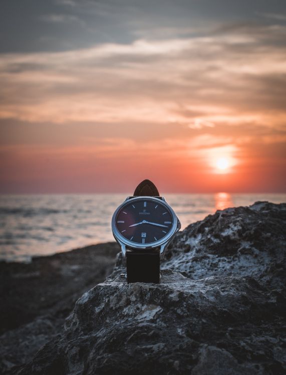 Black and White Analog Watch on Gray Rock Near Sea During Sunset. Wallpaper in 3753x4926 Resolution