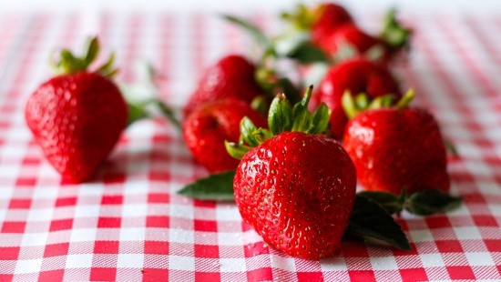 Image red strawberries on white and red checkered textile
