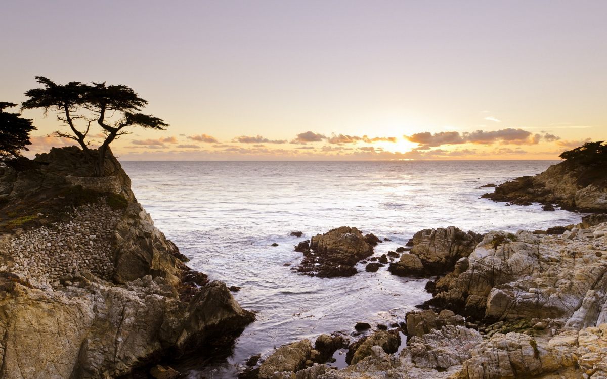 black rock formation on sea during sunset