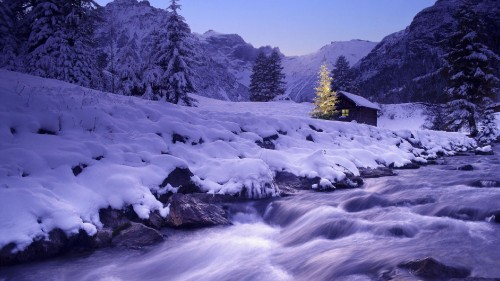 Image snow covered river near green trees and snow covered mountain during daytime