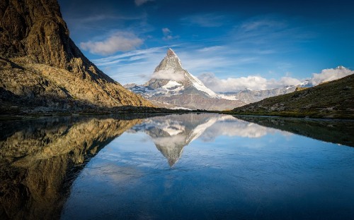 Image green mountain beside body of water under blue sky during daytime