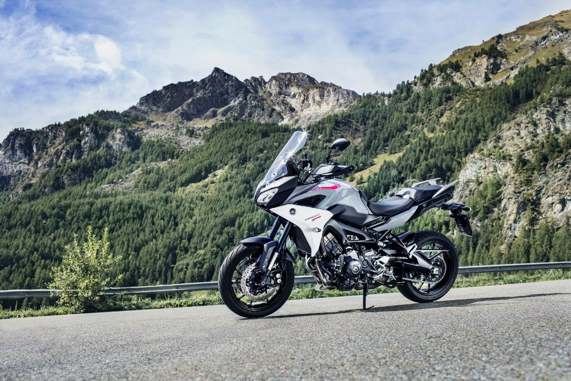 white and black sports bike parked on green grass field near green mountains during daytime