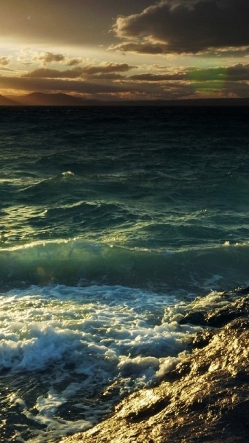 Image ocean waves crashing on shore during sunset