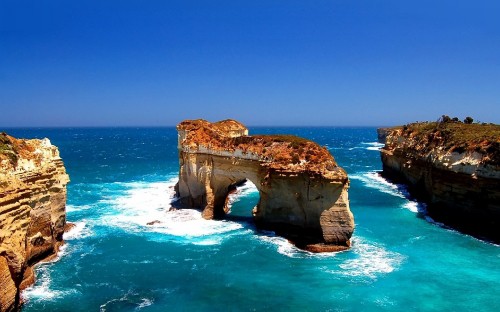 Image brown rock formation on blue sea under blue sky during daytime