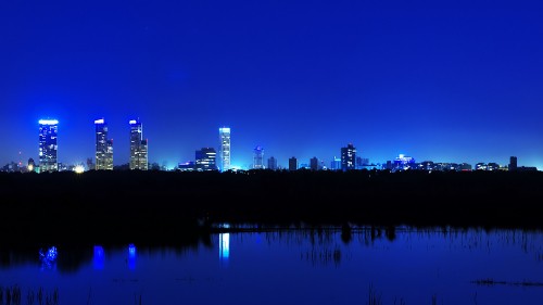 Image city skyline across body of water during night time