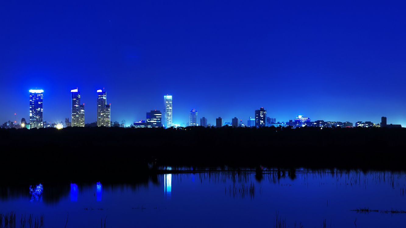 city skyline across body of water during night time