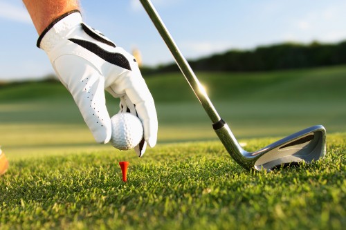 Image person in white pants and white nike shoes holding golf club