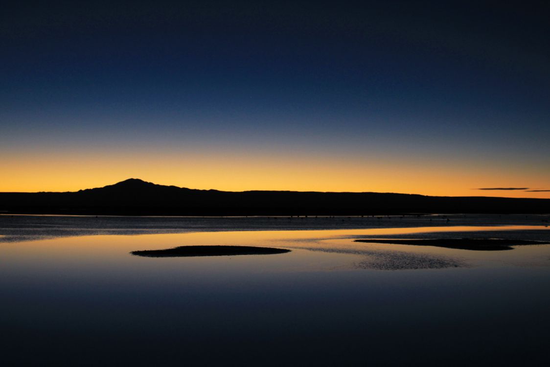 silhouette of mountain near body of water during daytime