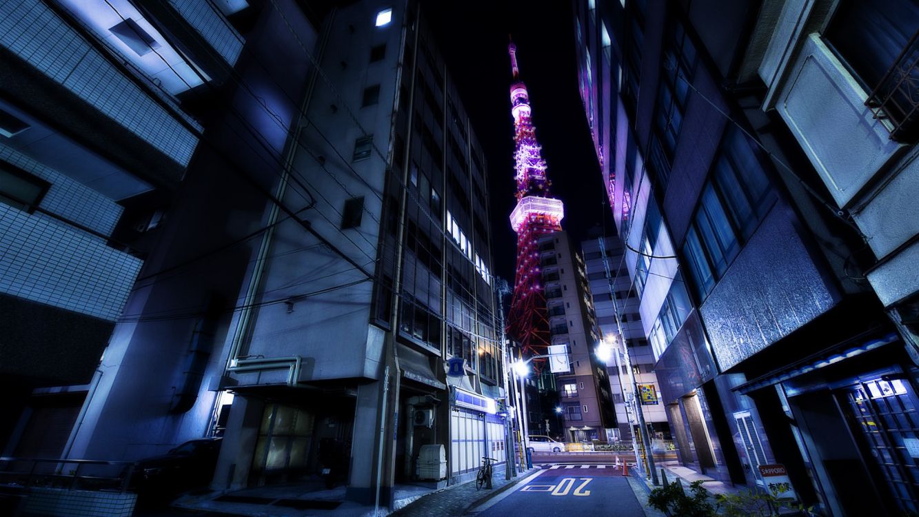 cars on road in between high rise buildings during night time