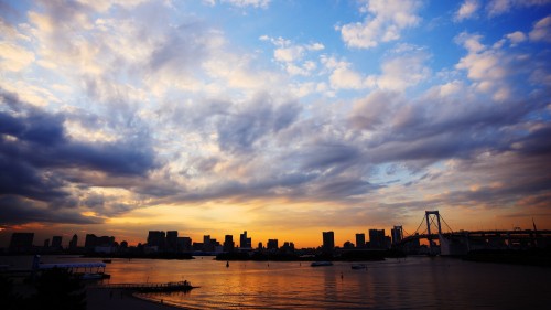 Image silhouette of city buildings near body of water during sunset