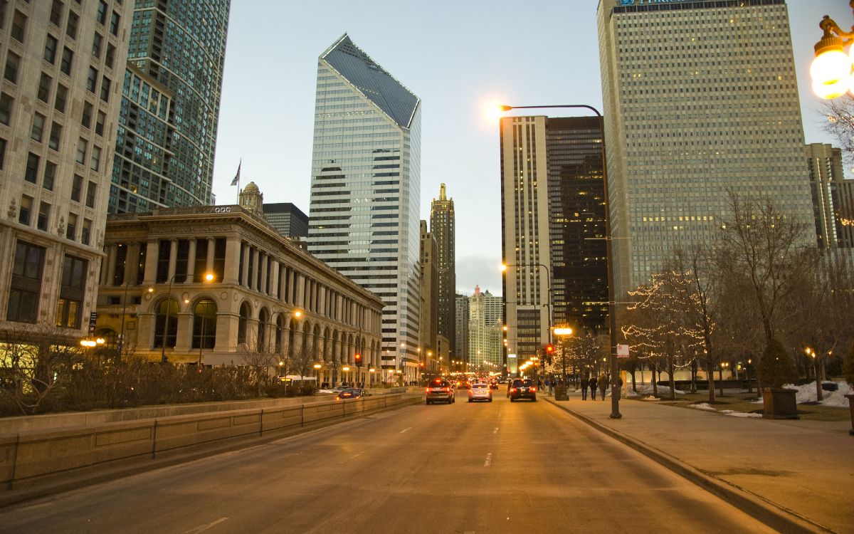 cars parked on side of the road near high rise buildings during night time