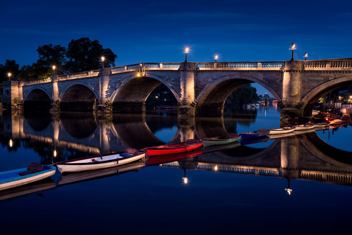 Braunes Und Rotes Boot Auf Dem Fluss Unter Der Brücke Während Der Nacht. Wallpaper in 2560x1708 Resolution