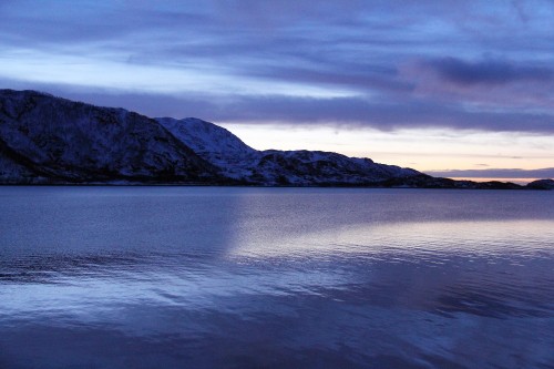 Image body of water near mountain under cloudy sky during daytime