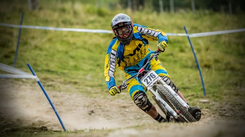 Image man in blue and yellow jacket riding white and blue motocross dirt bike