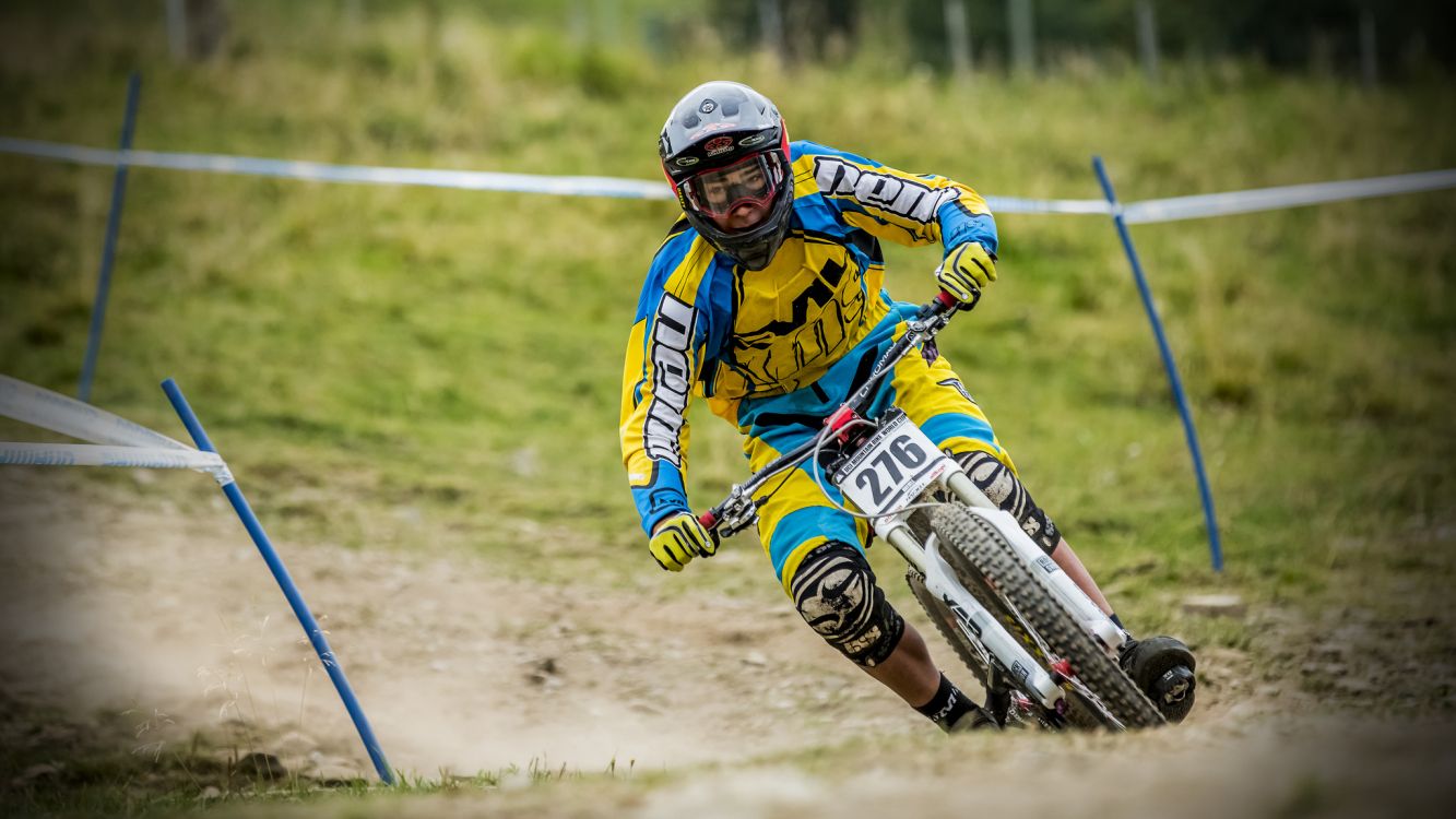 man in blue and yellow jacket riding white and blue motocross dirt bike