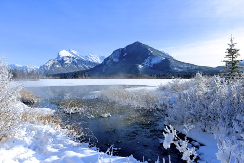 Image snow covered mountain near lake under blue sky during daytime