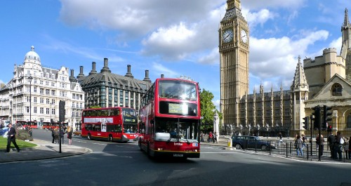 Image red double decker bus on road near brown concrete building during daytime