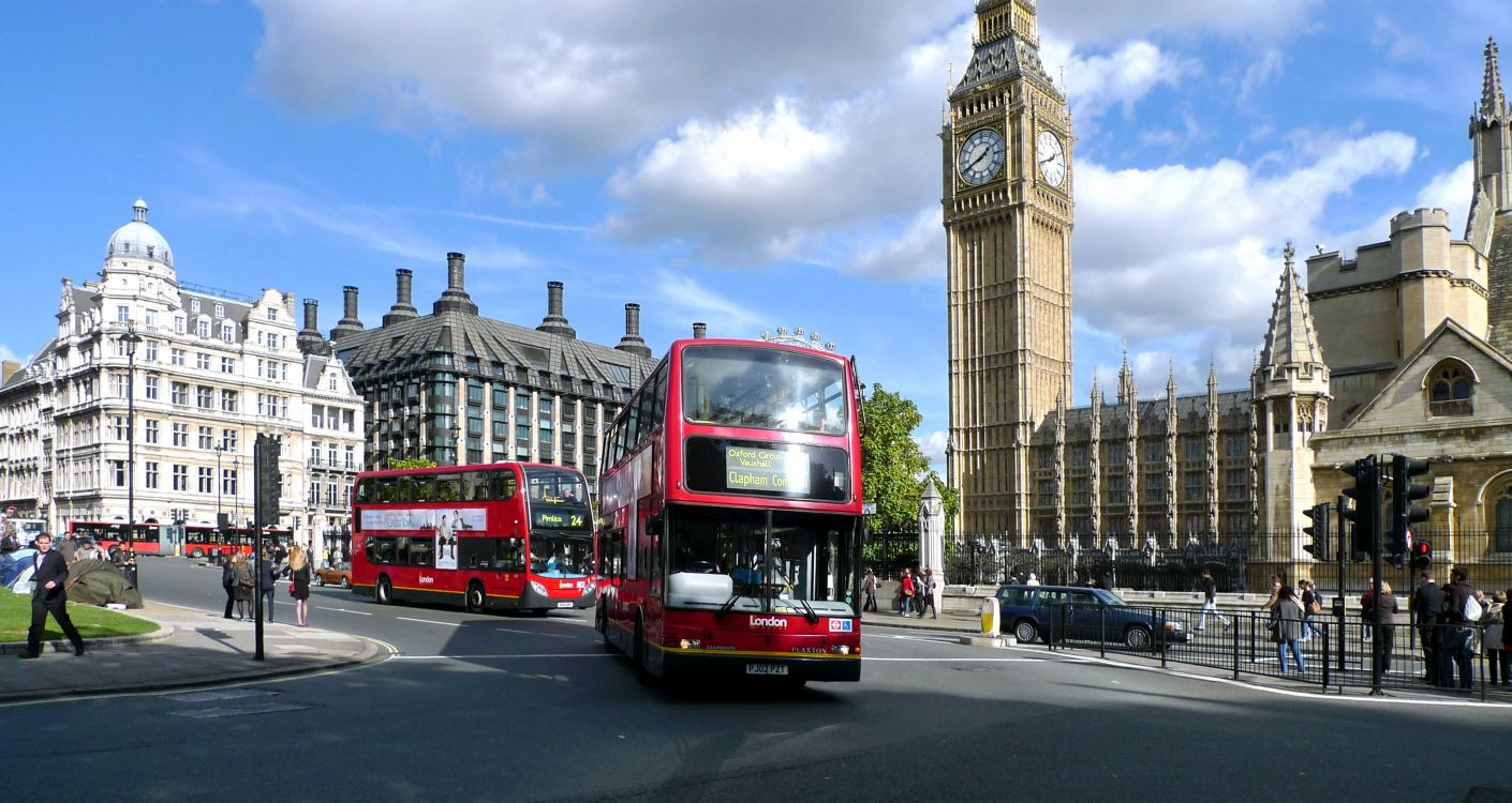 red double decker bus on road near brown concrete building during daytime