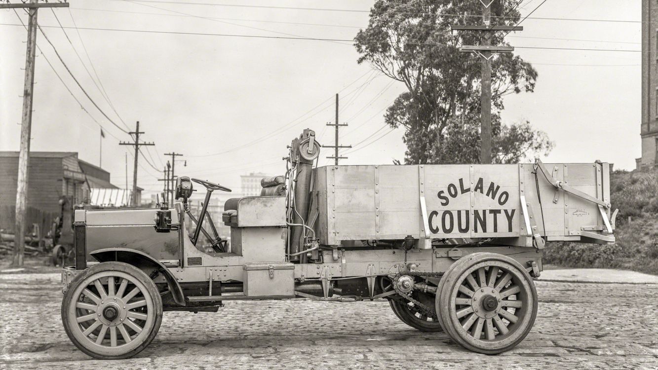 grayscale photo of a trailer truck parked near trees