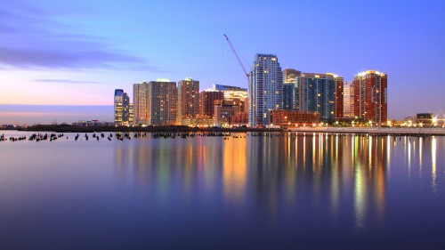 Image city skyline across body of water during night time