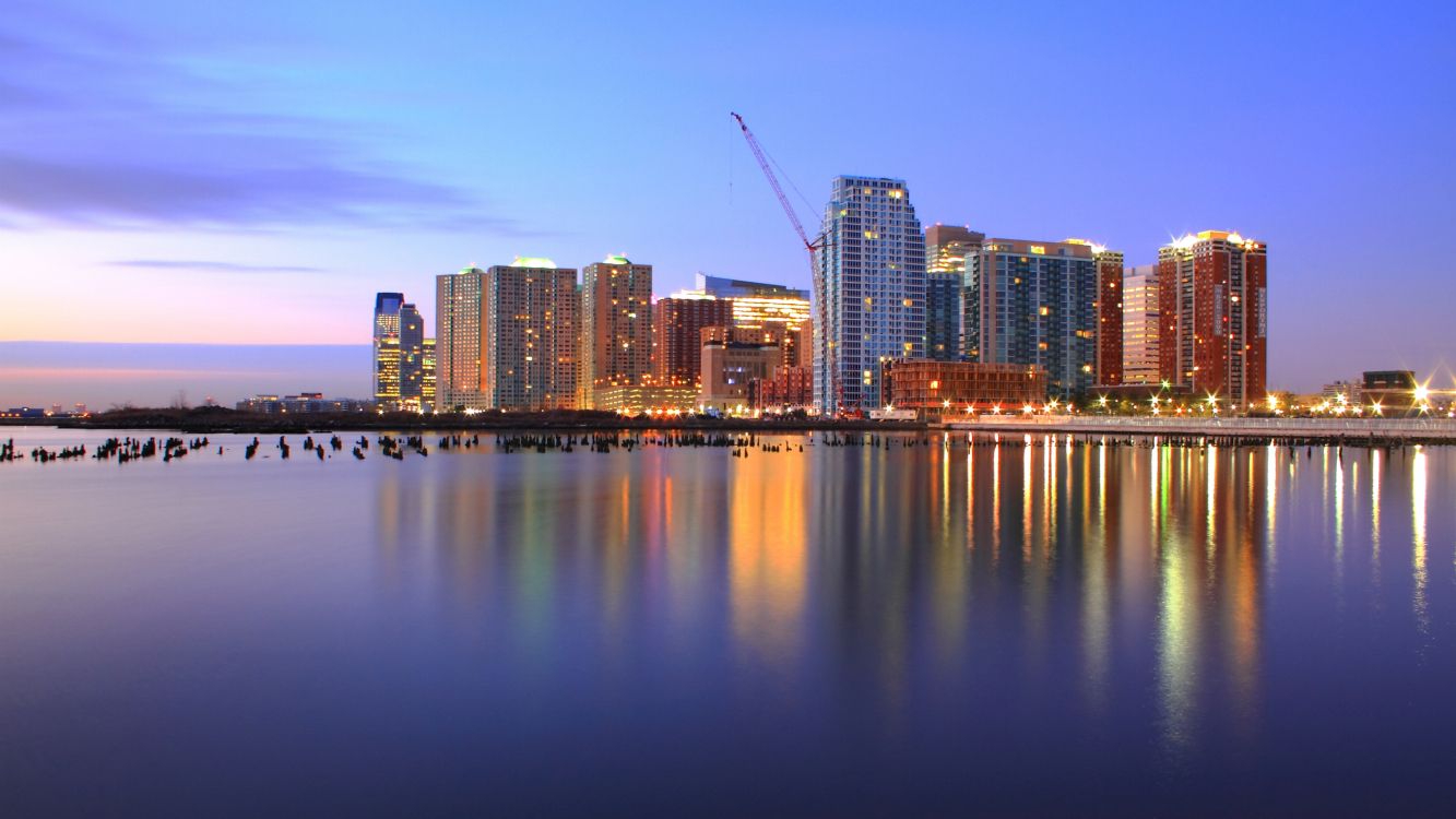 city skyline across body of water during night time