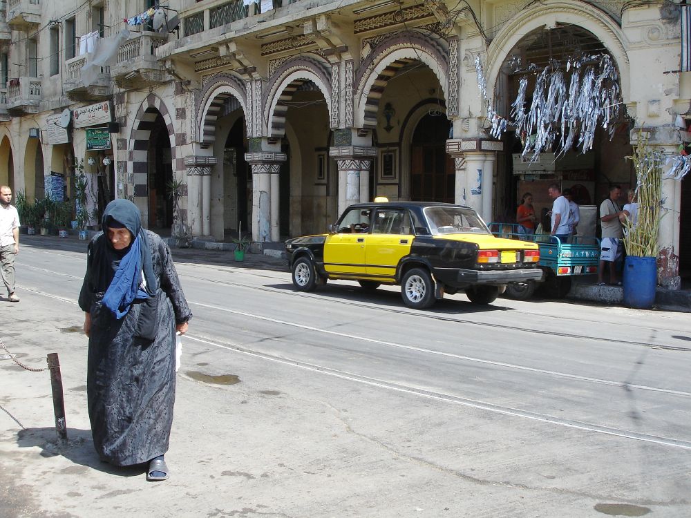 woman in gray coat walking on sidewalk during daytime