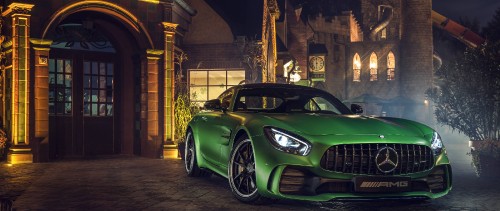 Image green car parked beside brown brick building