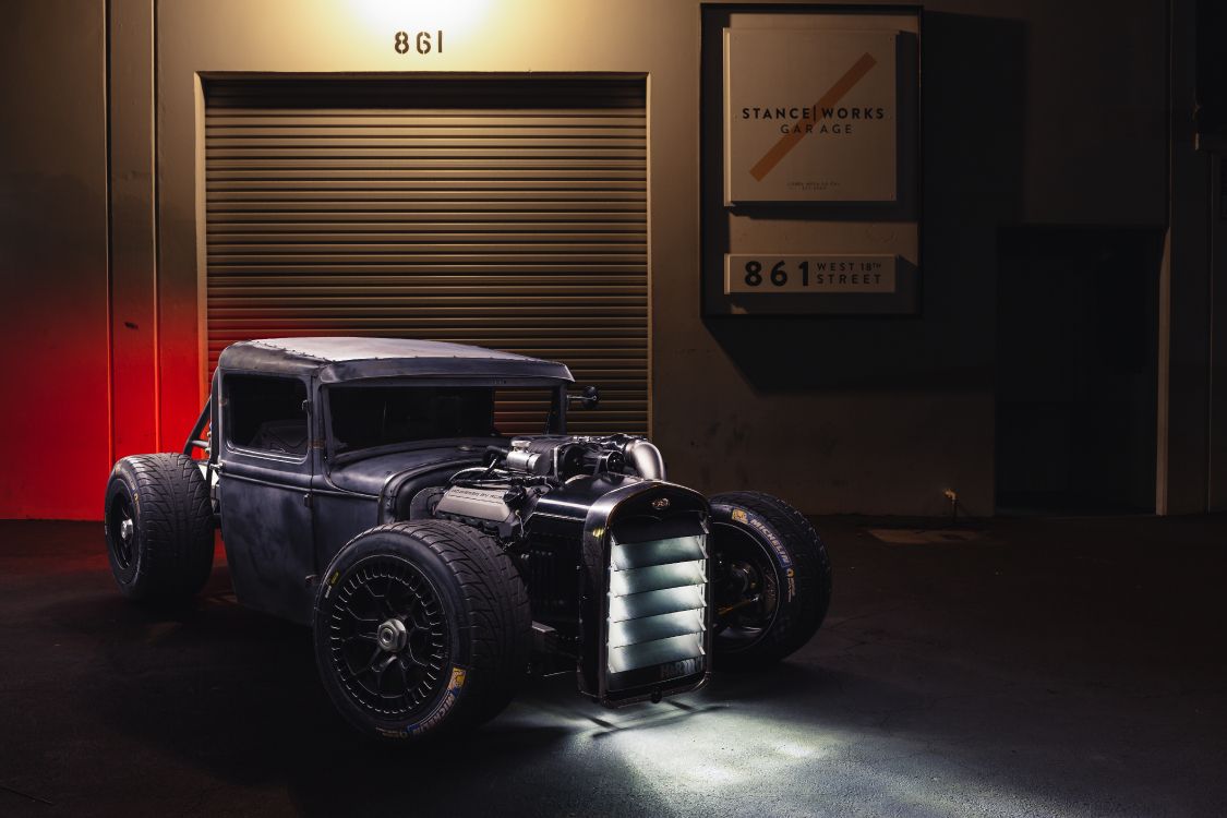 black vintage car in front of brown wooden wall