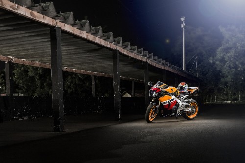 Image red and black sports bike parked on gray concrete pavement during night time