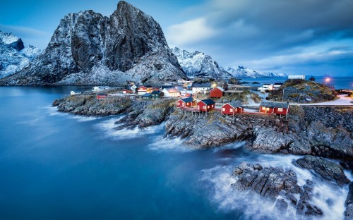 Image houses near rocky mountain and body of water during daytime