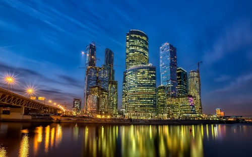 Image city skyline across body of water during night time