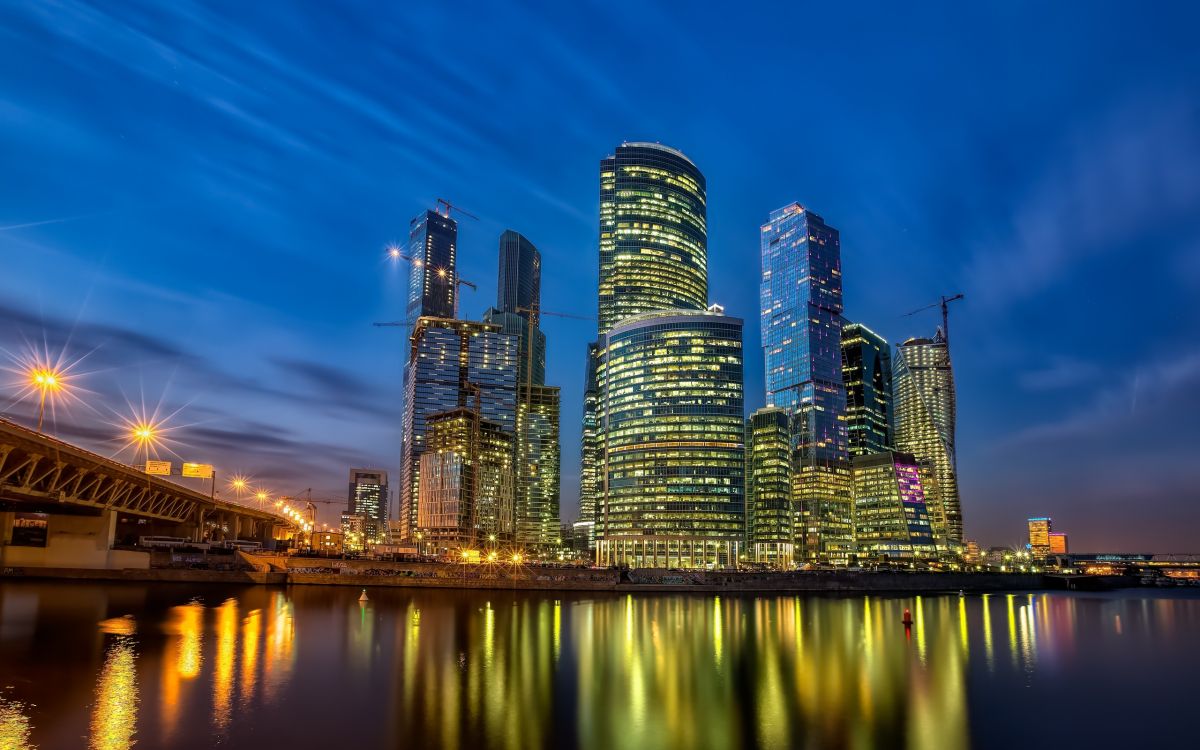 city skyline across body of water during night time