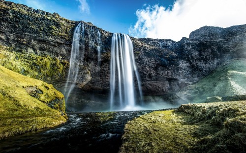 Image waterfalls on green grass field under blue sky during daytime