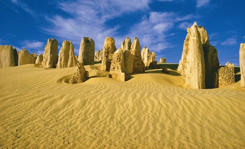 Image brown rock formation on brown sand under blue sky during daytime