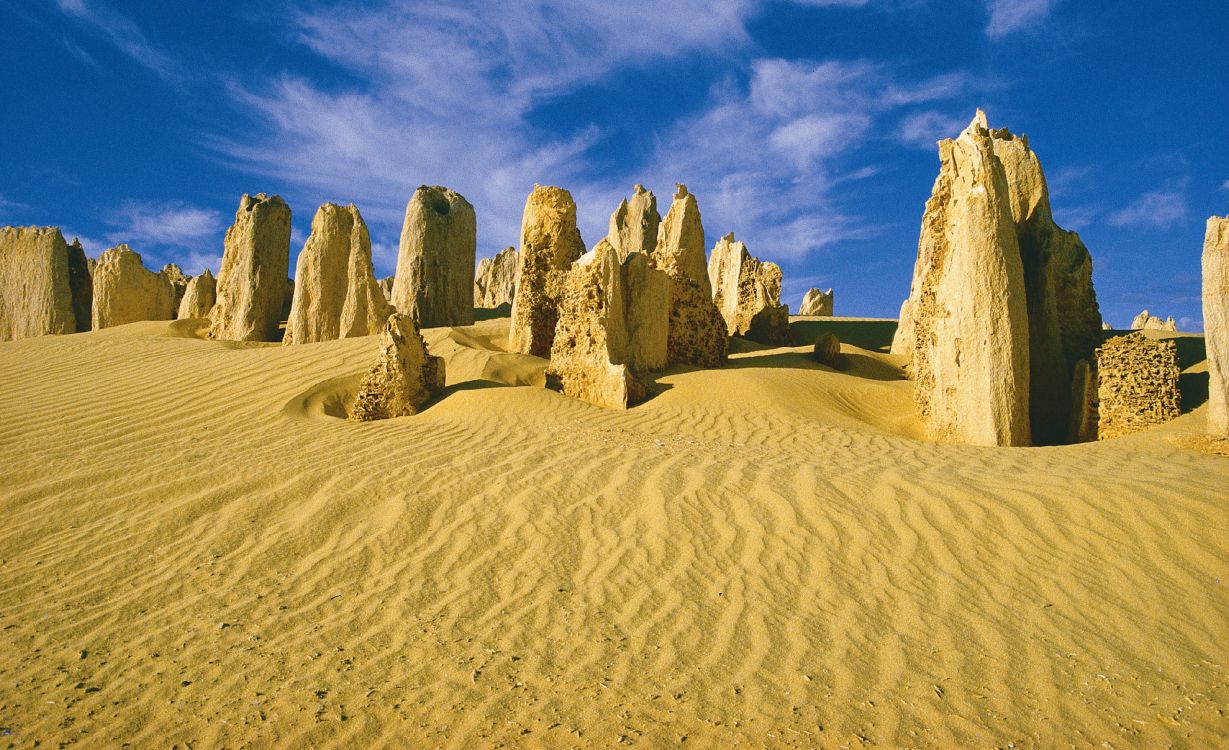 brown rock formation on brown sand under blue sky during daytime