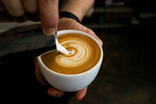 Image person holding white ceramic cup with brown liquid