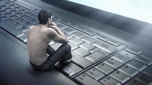 Image topless man in black denim jeans sitting on black and gray laptop computer