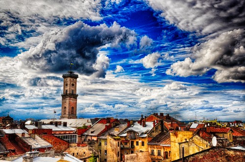 Image brown and white concrete building under blue sky and white clouds during daytime