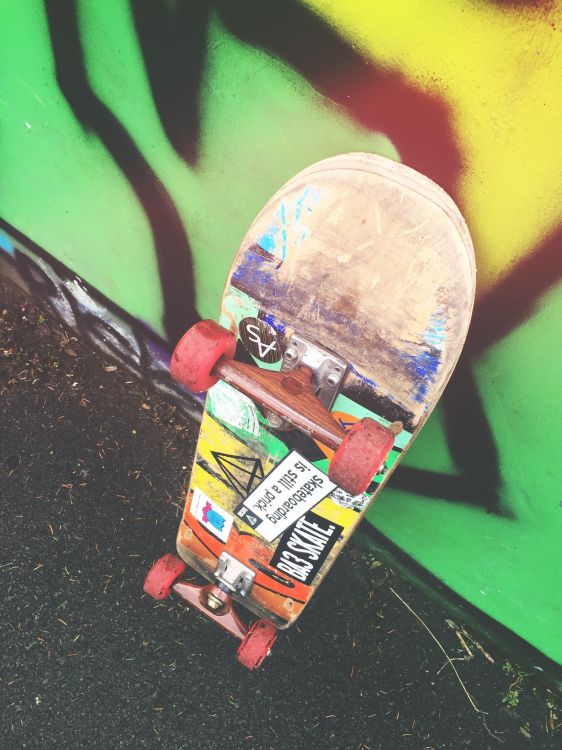 Skateboard Rouge et Jaune Sur Mur Vert. Wallpaper in 2448x3264 Resolution